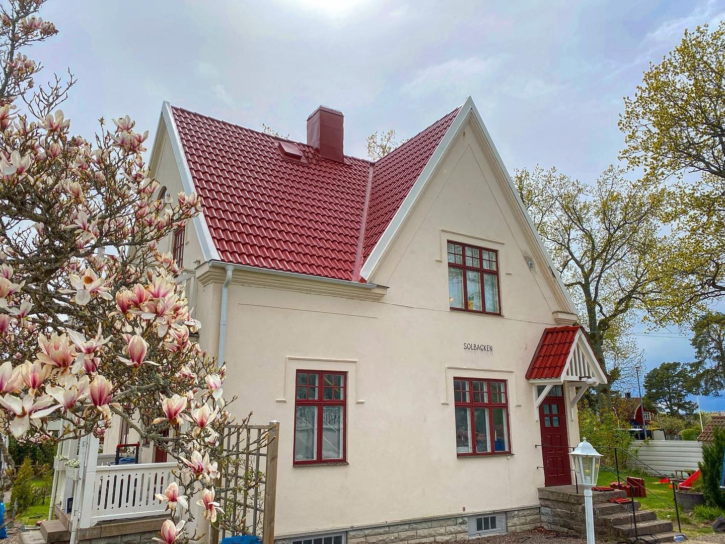 Ljus villa med rött tegeltak och flera takfall
